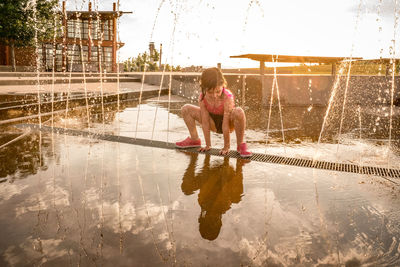 Full length of woman with reflection in water against sky