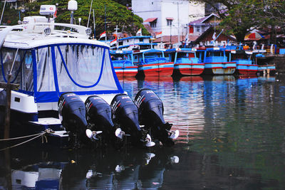 Boats moored in river with city in background