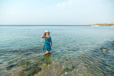 Rear view of woman standing in sea against sky