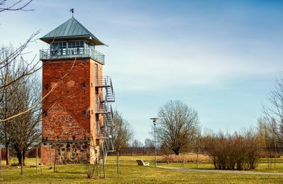 Scenic view of watch tower in grassy field against cloudy sky