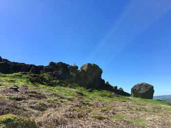 Rock formations on landscape against clear blue sky