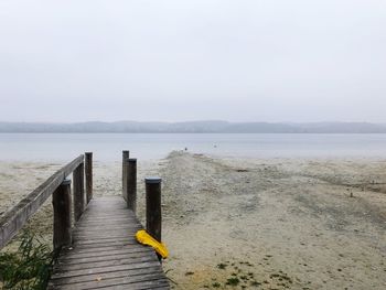 Wooden posts on beach against sky