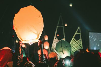 People with illuminated lanterns at night