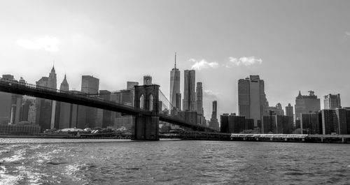 Skyscrapers by river against sky in city