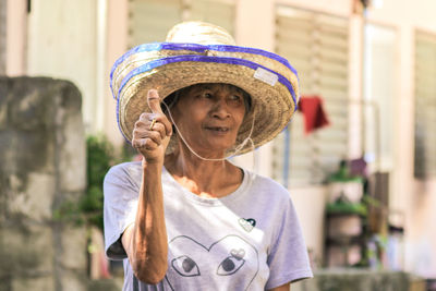 Woman wearing hat and gesturing while standing outdoors