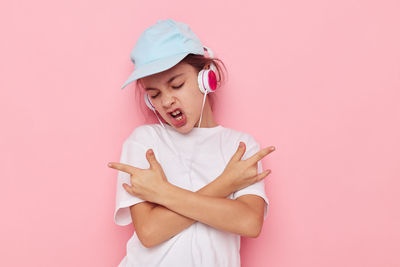 Portrait of young woman holding gift against pink background