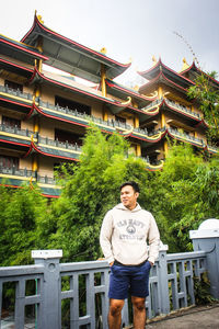Portrait of young man standing against building