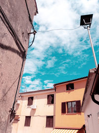 Low angle view of street light by building against sky