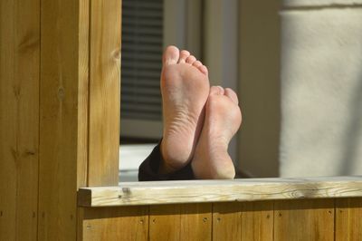 Low section of person resting on wooden window