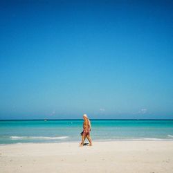 Woman on beach against clear blue sky