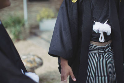 Midsection of woman holding umbrella standing outdoors