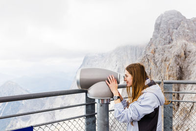 Young women looks at mountain views in binoculars from observation