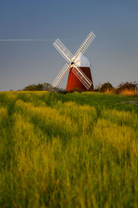 Traditional windmill on field against clear sky