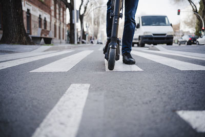 Man riding push scooter on road