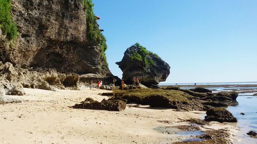 Rock formations on beach against clear sky