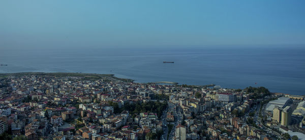 High angle view of cityscape by sea against clear sky