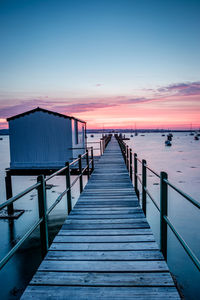 Wooden pier on sea against sky during sunset
