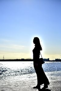 Side view of silhouette woman standing at beach against sky