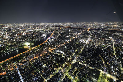 High angle view of illuminated city buildings against sky at night