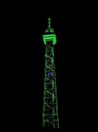 Illuminated tower against clear sky at night