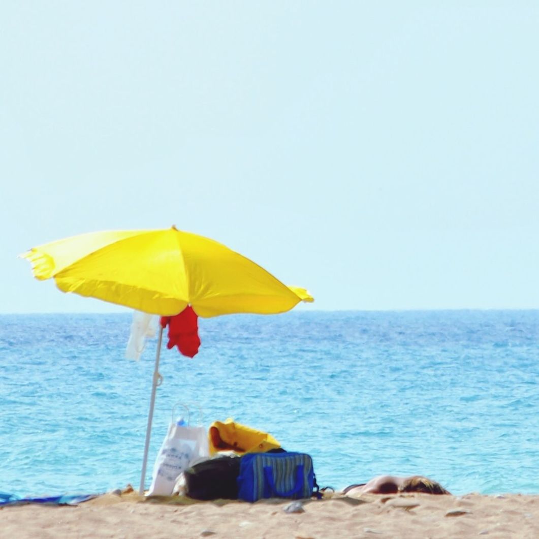 yellow, blue, leisure activity, lifestyles, men, clear sky, copy space, multi colored, umbrella, holding, wall - building feature, day, outdoors, standing, rear view, close-up, toy, person