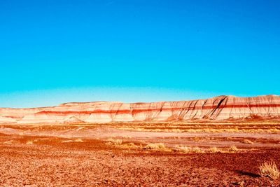 Scenic view of desert against clear blue sky