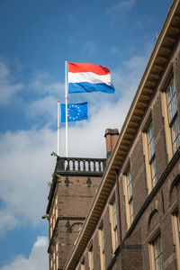 Low angle view of flags on building against sky