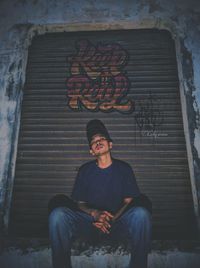 Man sitting on wall of building