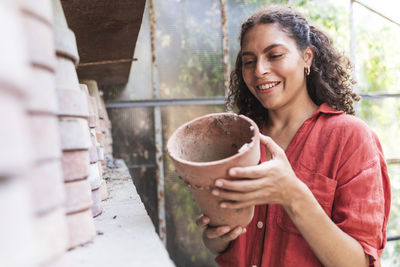 Portrait of a smiling young woman holding ice cream outdoors