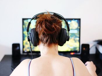 Rear view of woman playing game on computer at home