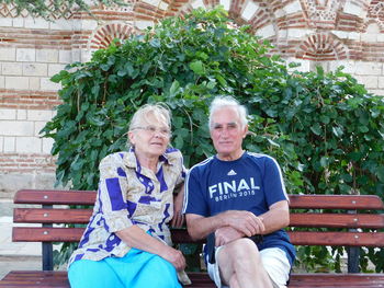 Man and woman sitting on bench in park