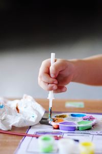 Cropped hand of girl holding paintbrush at table