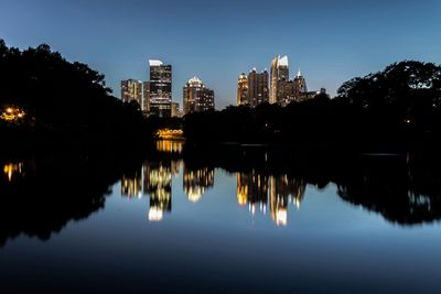 Reflection of skyline in piedmont park lake against clear sky