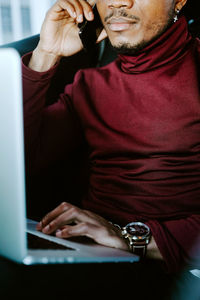 Midsection of man using mobile phone while sitting on table