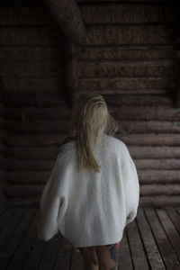 Side view of young woman standing against wall