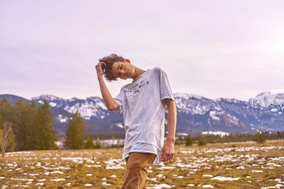 Young man with head cocked standing on field during winter