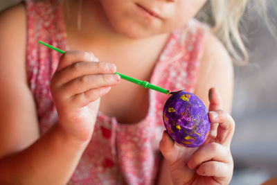 Midsection of girl painting easter egg at home