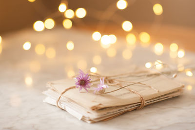 Laced paer handwriten letters with dry flowers over glow lights at background on table in room