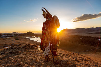 Boy standing on land against sky during sunset