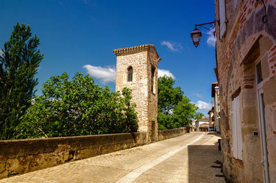 Footpath amidst buildings against clear blue sky