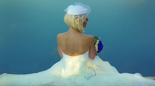 Rear view of bride standing against blue background