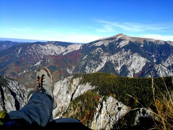 Low section of man standing on mountain against sky