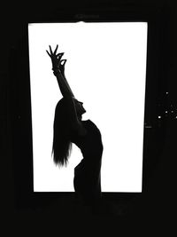Side view of silhouette woman with arms raised