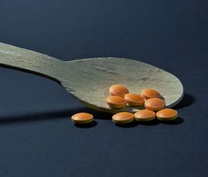 Close-up of pills and wooden spoon over black background