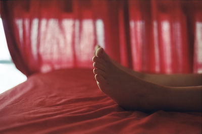 Low section of woman lying on bed at home