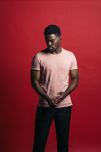 Portrait of young man standing against red background