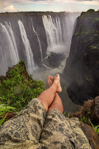 Low section of man relaxing on rock