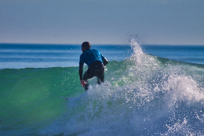 Man surfing in sea against sky