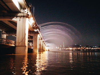 Illuminated bridge over river at night