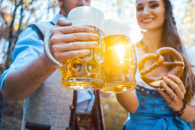 Couple toasting beer glasses while standing outdoors